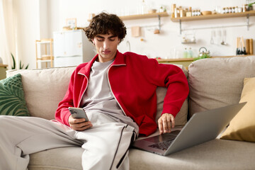 Stylish young man engages with his smartphone while relaxing on a cozy sofa