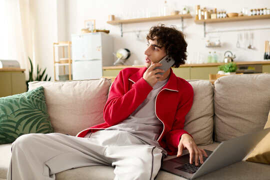 Handsome man in stylish attire engages in a phone conversation while relaxing at home - Powered by Adobe