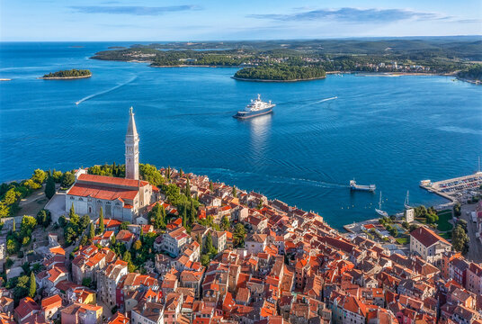 Aerial view of the charming terracotta rooftops tumbling down towards the sea next to the towering church of St. Euphemia, Rovinj, Istria, Croatia.
