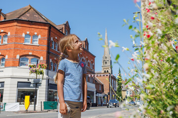Child in striped shirt enjoys sunny day at urban scenery, UK