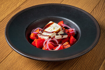 A vibrant salad features juicy tomatoes, crisp onions, and creamy feta, all elegantly arranged