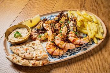 A vibrant seafood platter showcases grilled shrimp, golden fries, flatbread, and lemon
