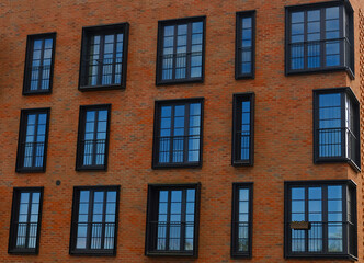 Exterior of modern brick house object. Architectural detail of a skyscraper, close-up on the windows. Real estate, residential apartments and offices. Living apartments or office building architecture