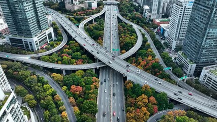 Aerial view of a complex highway interchange in a city with autumn foliage and skyscrapers - Powered by Adobe
