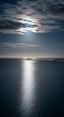 Obraz premium A serene seascape with the sun shining through clouds reflecting on the water surface creating a glow