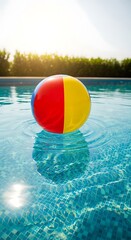 A colorful beach ball floating in a swimming pool on a sunny day with trees in the background