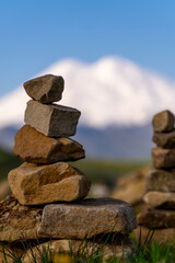 Rock Stacking Mountain Balance: Cairns mark trail with Elbrus peak backdrop in daytime for navigation.