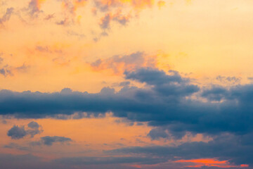 Obraz premium dark cloudscape at sunset. orange-purple clouds on a yellow-blue gradient of sky in evening light. dramatic weather change. wind forecast background. place for copy space. narrow telephoto shot