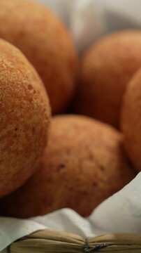 Delicious Colombian bu&ntilde;uelos in a close-up vertical video. Golden brown, crispy texture in soft lighting, showing the rich details of this traditional fried snack.