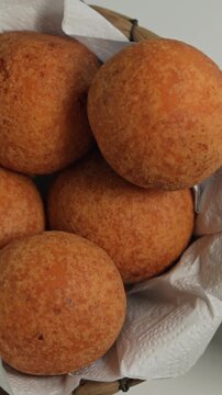 Delightful close-up shot of golden, crispy bu&ntilde;uelos nestled in a basket. Warm lighting accentuates texture, perfect for social media in a vertical video format.