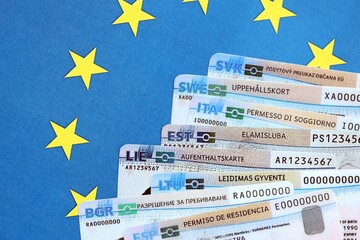 Permanent resident or residence permit cards lies on European Union flag. Paper specimen cards close up