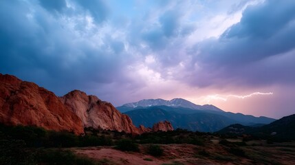 Naklejka premium A dramatic lightning strike illuminates distant snow capped mountains and red rock formations under a stormy twilight sky