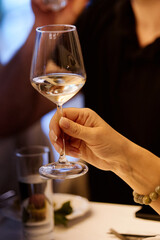 Hand with a glass of wine in the night atmosphere of the restaurant