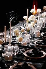 Luxurious setting of dark restaurant tables with candles and fresh flowers