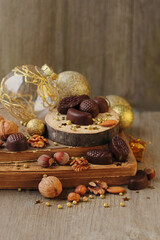 festive composition with chocolate candies, nuts, christmas decorations, old books on wooden table. vintage style. New Year, Christmas, Advent holidays