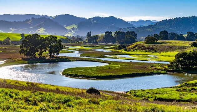 Scenic vista with winding river, lush green fields, and rolling hills under a bright, clear sky. The sunlight reflects on the water - Powered by Adobe
