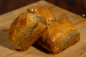 Three golden pieces of baklava glisten atop a wooden surface