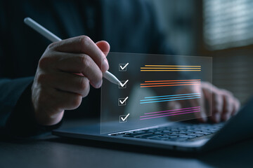 Businessman using digital pen to check boxes on virtual checklist screen over laptop. Concept of...