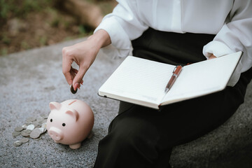 A woman wearing a white shirt is saving money by putting a coin into a pink piggy bank, symbolizing financial planning and saving for the future.