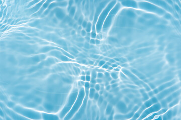 Blue water with ripples on the surface. Defocus blurred transparent blue colored clear calm water surface texture with splashes and bubbles. Water waves with shining pattern texture background.