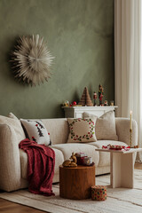 Minimalist Christmas living room with a soft beige sofa, red blanket, and green wall. Peaceful and inviting holiday styling.