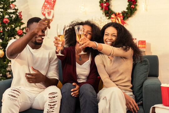 Group of African friend or family celebrating joyfully during the holidays, raising champagne glasses for a New Year's or Christmas toast.