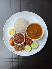 A nasi lemak kari kambing set is a Malaysian meal featuring fragrant rice cooked in coconut milk, served with a rich and aromatic lamb curry.