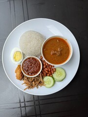 A nasi lemak kari kambing set is a Malaysian meal featuring fragrant rice cooked in coconut milk, served with a rich and aromatic lamb curry.