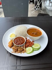 A nasi lemak kari kambing set is a Malaysian meal featuring fragrant rice cooked in coconut milk, served with a rich and aromatic lamb curry.