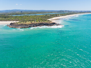 Aerial views of Fingal headland with the causeway rock formations visible under the shallow water at Fingal Head, New South Wales, Australia