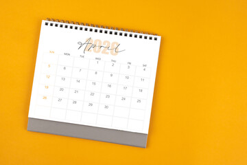 Top view of April 2026 desk calendar on yellow color background.