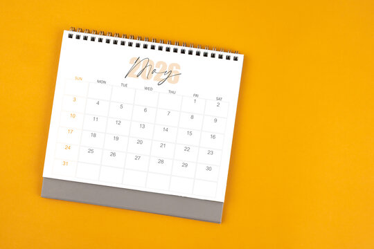 Top view of May 2026 desk calendar on yellow color background.
