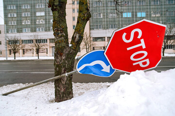 Bent stop sign damaged by snowplow or car accident during winter season creating road safety hazard and warning signal deformation. Broken stop sign caused by icy road conditions, snowplow collision