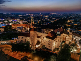 Aerial evening view of Wawel Castle in Krak&oacute;w, Poland, with illuminated walls and Vistula River