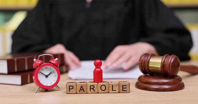 Judge reviewing parole applications in a courtroom with books and gavel present