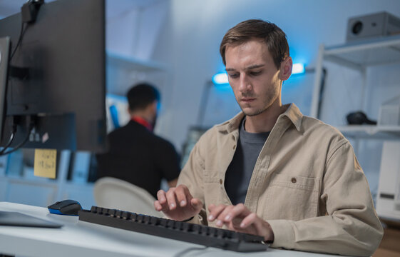 Professional Male Software Developer, Computer Programmer Concentrated on Software Development, Coding Application, Analyzing Cyber Security Code and Programming Task Sitting at Desk with Computer.