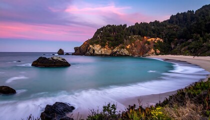 Scenic coastal panorama at sunset showcasing a secluded cove with a rocky outcrop, sandy beach, and lush, green forested hills under a colorful sky