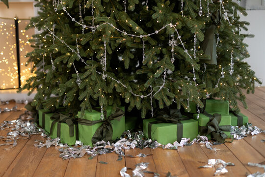 Many Christmas gifts on floor under fir tree. Xmas gifts under tree in decorated house interior. New Year. Green boxes with presents. Xmas tree with lights glowing garlands. Christmas at home.	
 - Powered by Adobe
