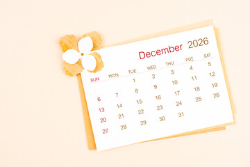December 2026 calendar with origami flower paper on beige color background.