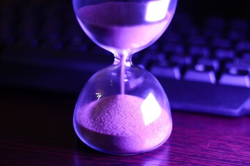 hourglass with the sand and computer keyboard time and work