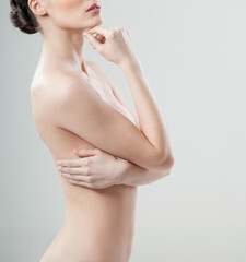 Fototapeta premium Beautiful young woman with clean skin nude topless breasts. Beautiful woman covering her nude breast. beautiful female figure. perfect skin.