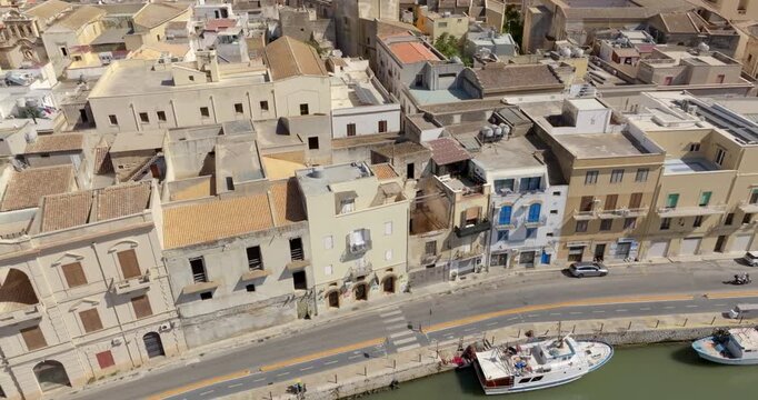Aerial view of houses and buildings built along a canal. It's Mazaro river, located in the historic center of Mazara del Vallo, in the province of Trapani, Sicily, Italy. It's a beautiful sunny day.