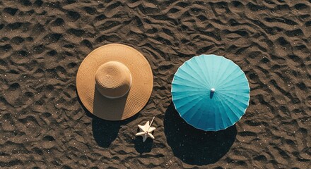Aerial view of a hat an umbrella and a starfish on dark sand beach