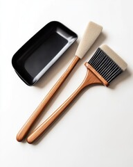 Two brushes with wooden handles, alongside a black tray