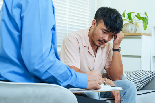 Asian adult man feeling emotional stressed during counseling session with senior therapist before wife joins therapy, expressing vulnerability seeking mental health support for relationship recovery