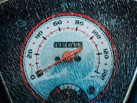 The motorcycle speedometer appears cracked from heat exposure, showing worn plastic texture and highlighting aging vehicle parts in daily use.