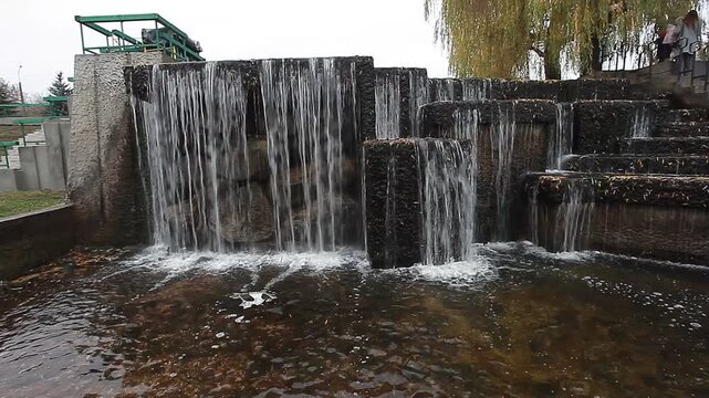 A river waterfall and stone architecture in a city park in spring