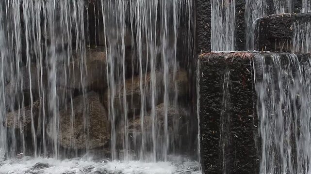 A river waterfall and stone architecture in a city park in spring