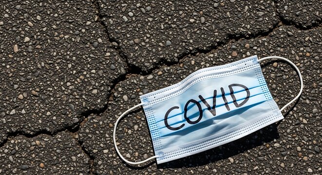 Discarded COVID-19 Mask on Cracked Asphalt - A Symbol of the Pandemic. - Powered by Adobe
