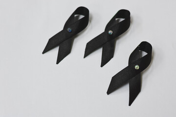 Three black ribbons with iridescent center pins on a white background.